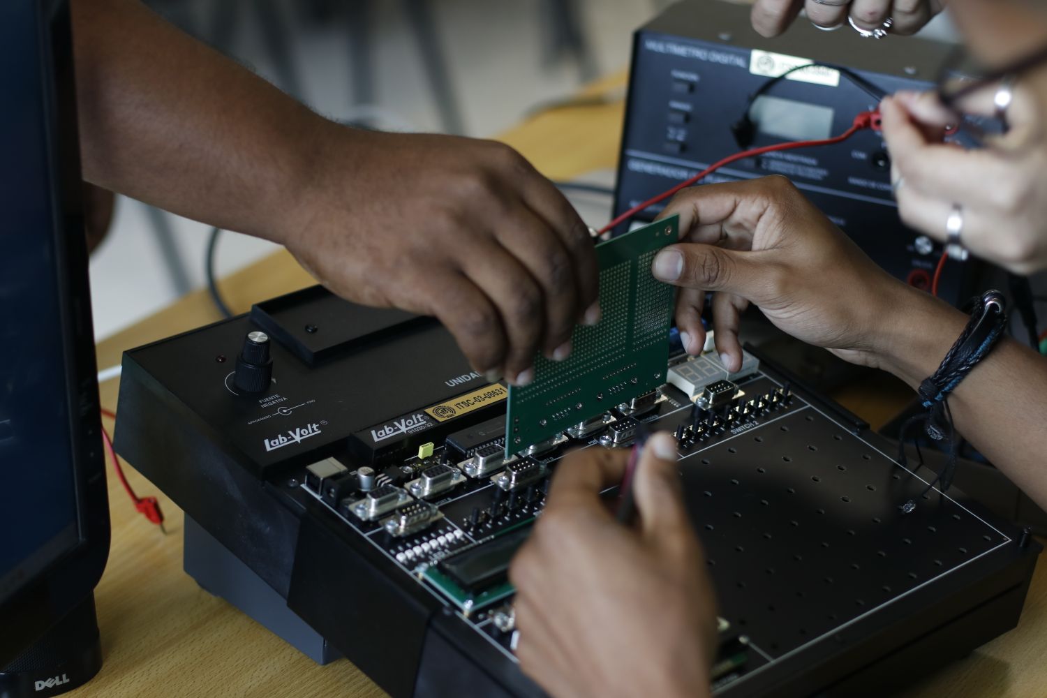Hands working with electronic components and a circuit board at a workbench